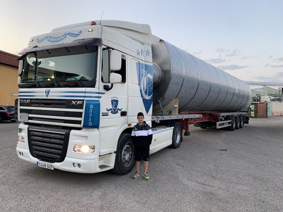 Un niño está parado frente a un gran camión blanco.