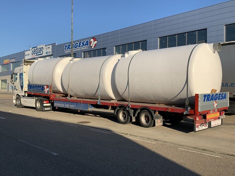 Un camión transporta tanques grandes en un remolque.