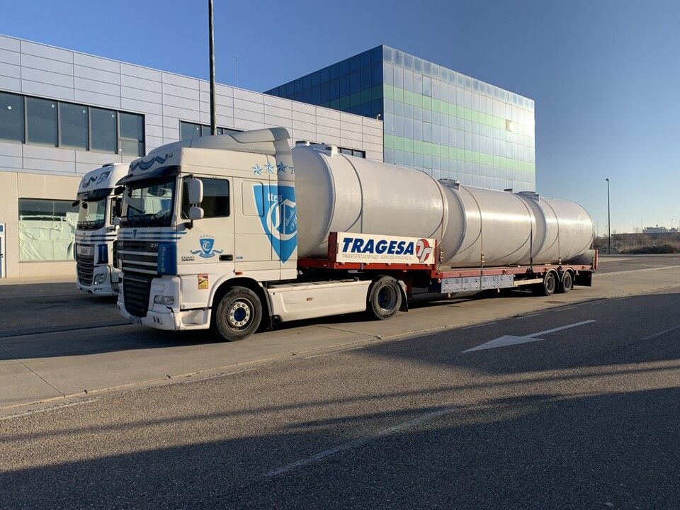 Dos camiones están estacionados al costado de la carretera frente a un edificio.