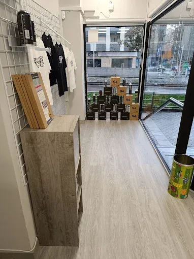 Una tienda con muchas botellas en el suelo y mucha ropa colgada en la pared.