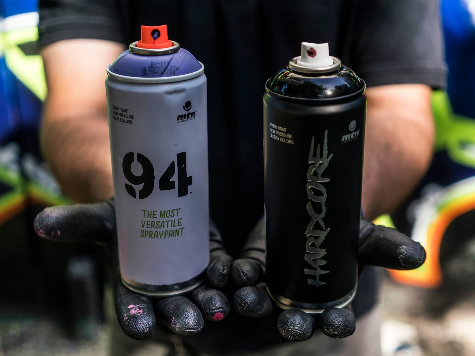 Una persona sostiene dos latas de pintura en aerosol en sus manos.