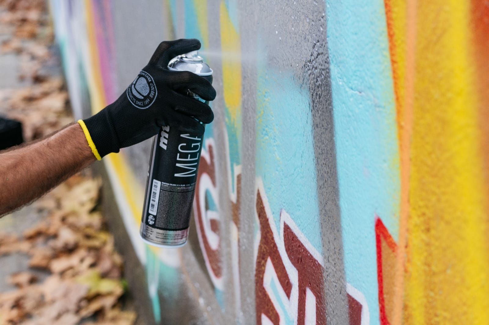Una persona está pintando grafitis con aerosol en una pared.