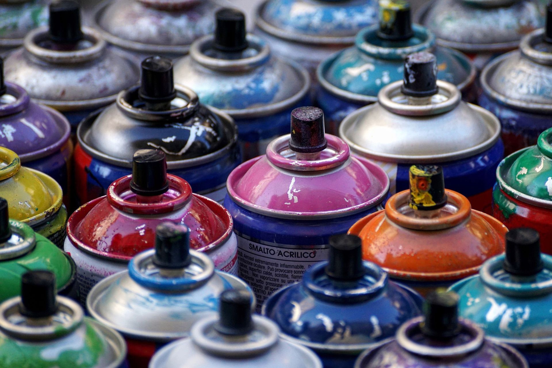 Un montón de latas de pintura en aerosol están colocadas una encima de otra.