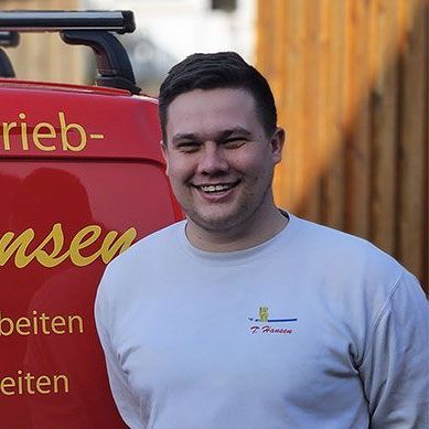 Ein Mann lächelt vor einem roten Lieferwagen.