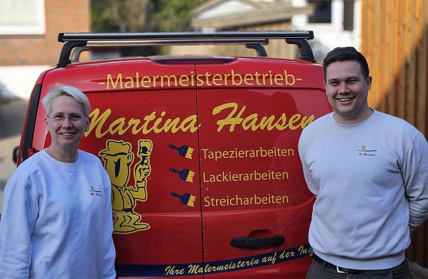 Ein Mann und eine Frau stehen vor einem roten Lieferwagen.