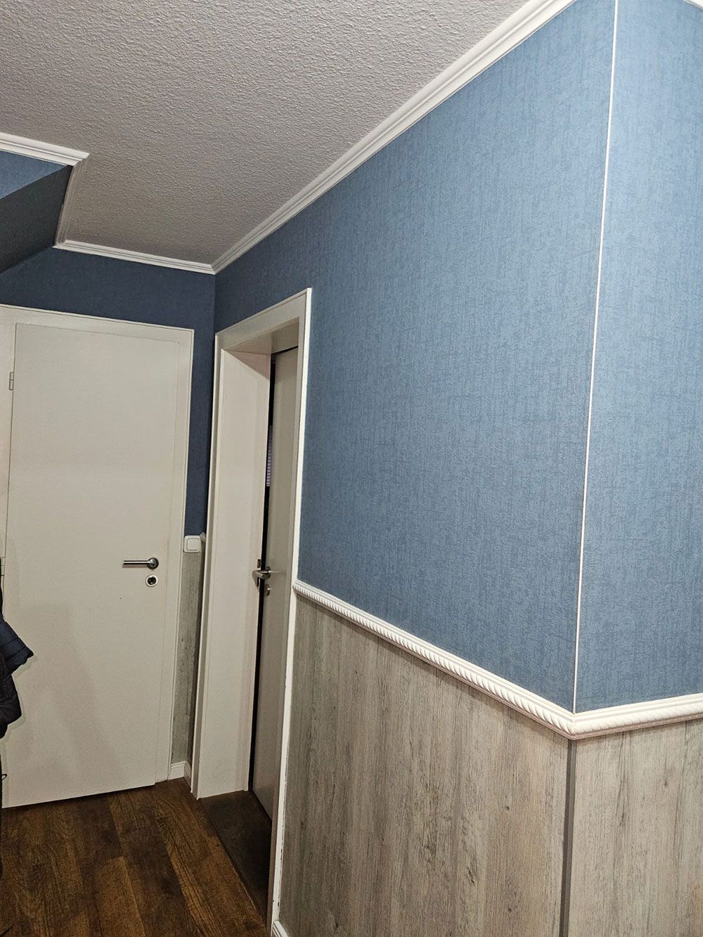 Ein Flur mit blauen Wänden und einer weißen Tür.