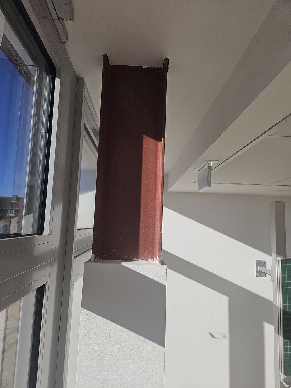 Ein rotes Objekt hängt von der Decke eines Zimmers neben einem Fenster.