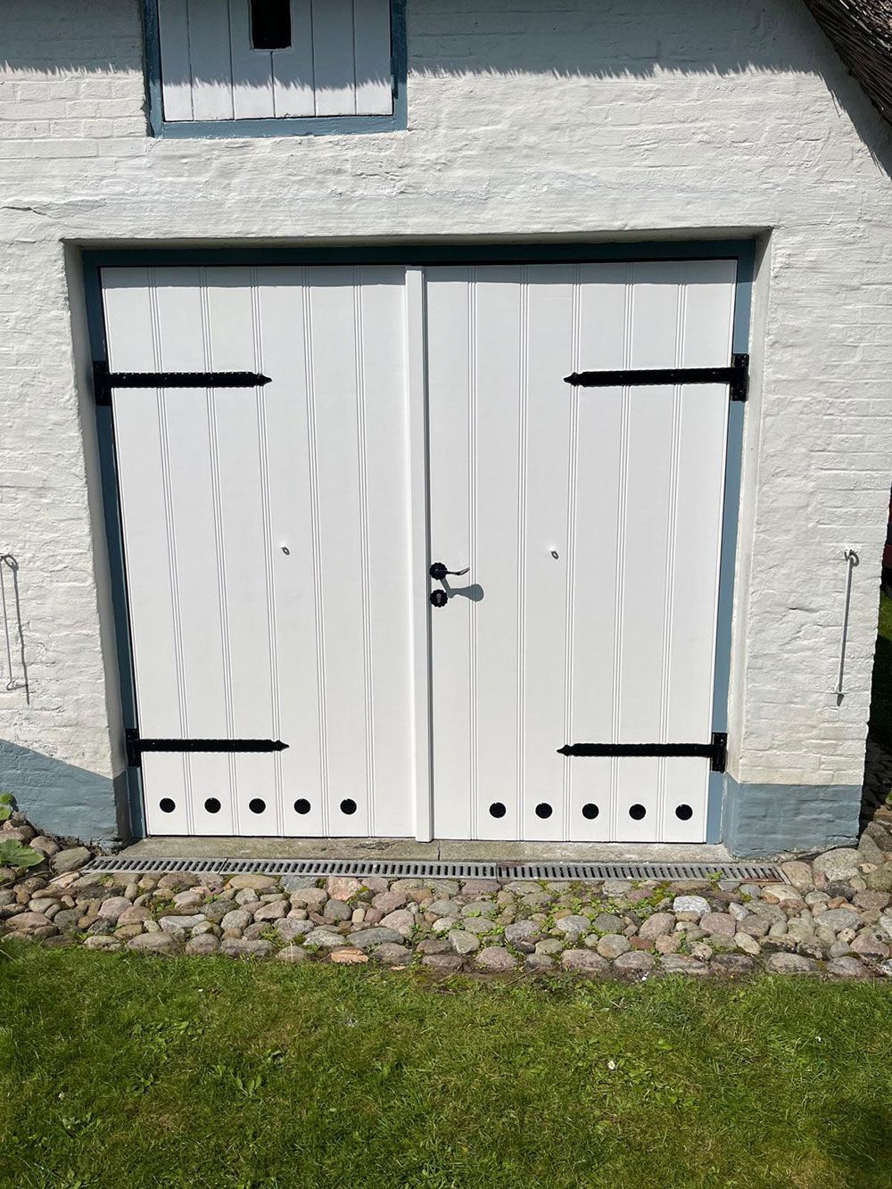 Ein weißes Garagentor mit schwarzen Bändern