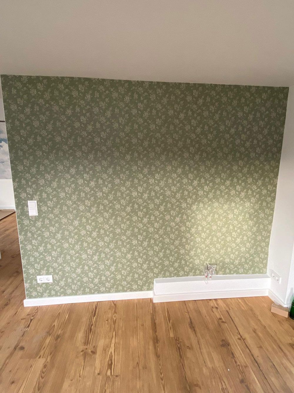 Ein Raum mit einer grünen Wand und einem Holzboden.