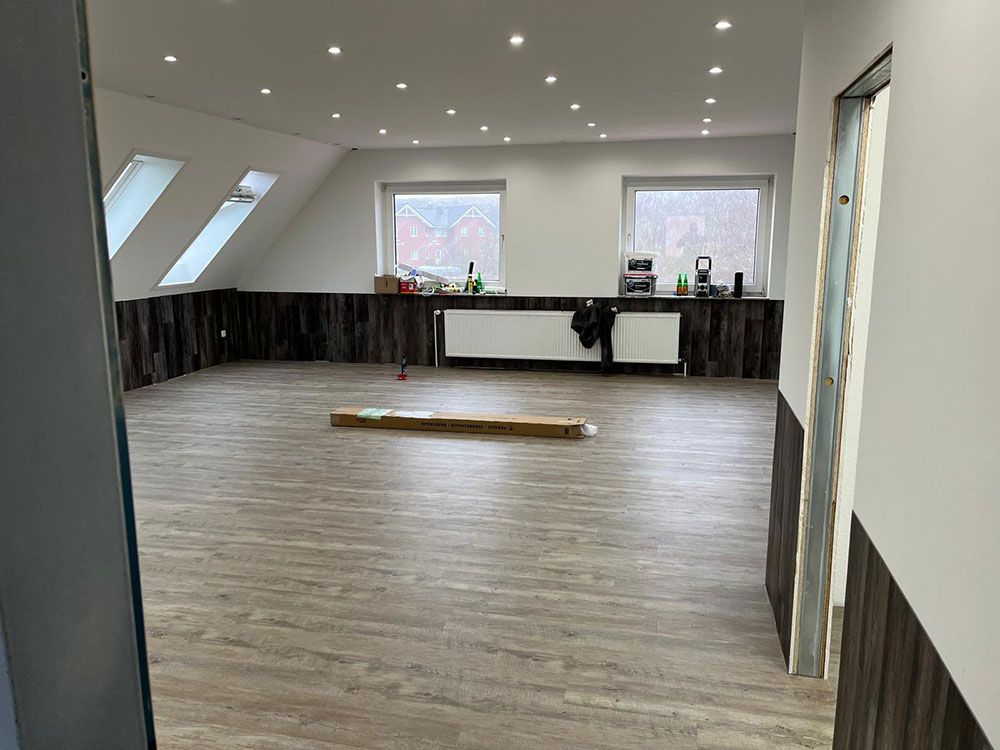 Ein großer Raum mit Holzboden und weißen Wänden.