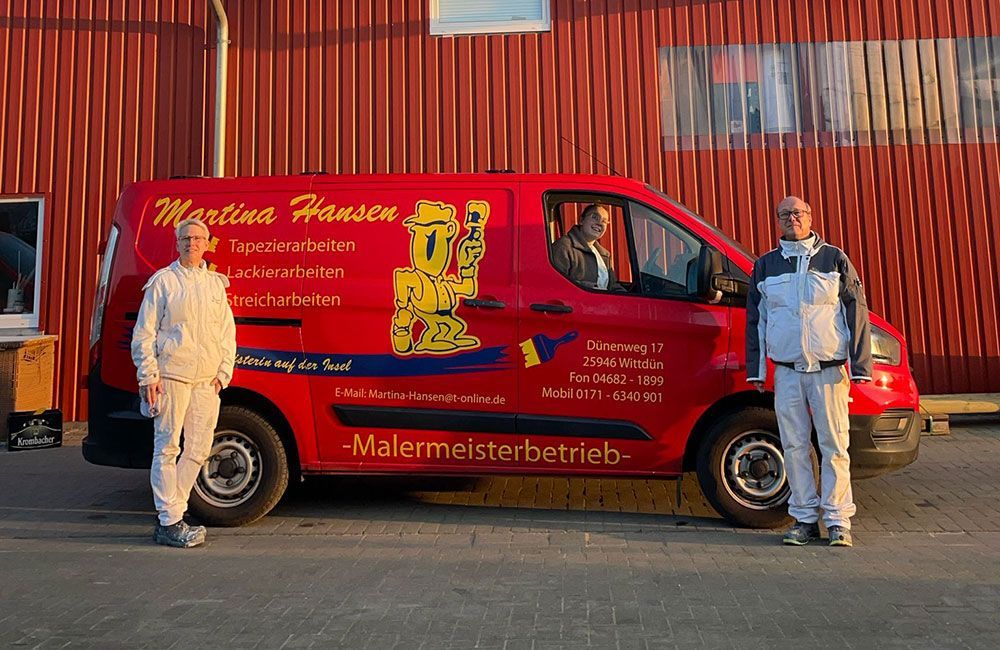 Zwei Männer stehen vor einem roten Lieferwagen mit der Aufschrift „Martina Hansen“