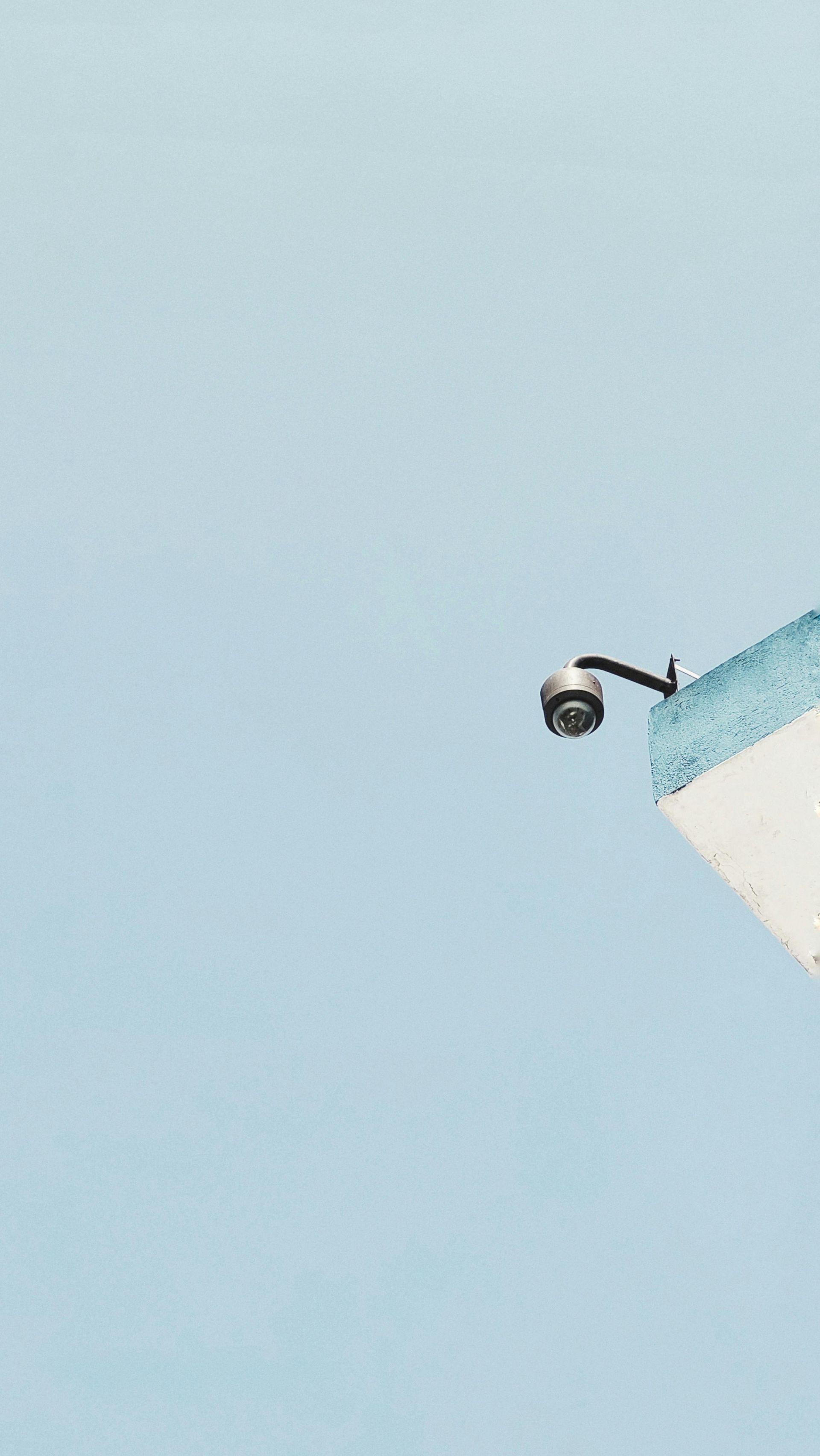 Cámara de seguridad instalada en la esquina de un edificio contra un cielo azul despejado