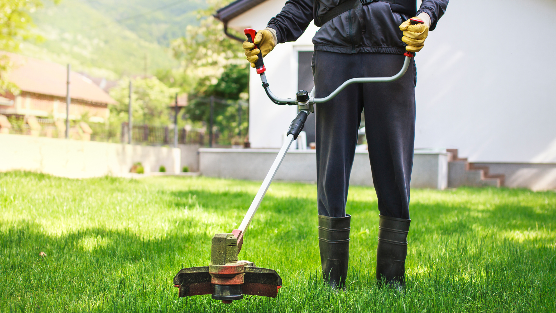 Une personne utilise un coupe-bordures pour tailler la pelouse dans un jardin ensoleillé.