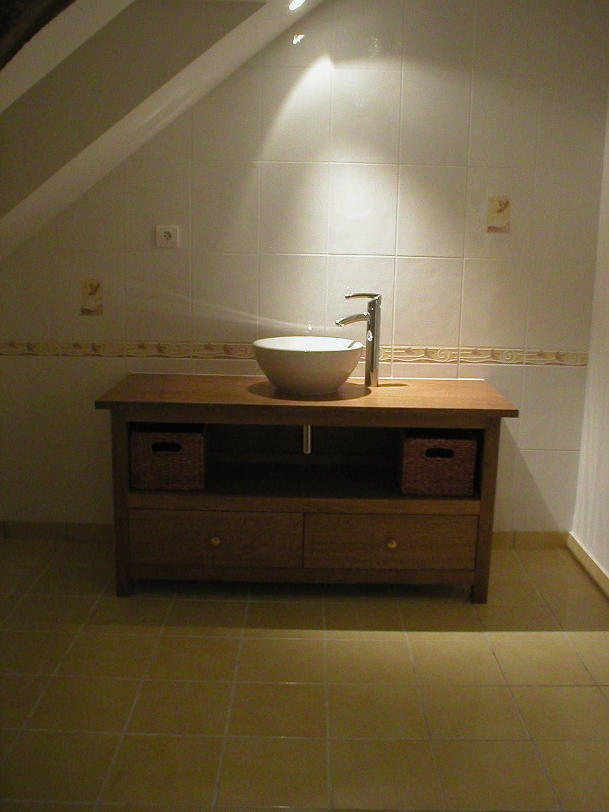 Meuble de salle de bains avec vasque à poser et miroir sur un mur carrelé, sous un éclairage chaleureux