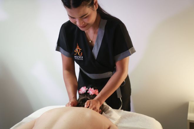 Une personne verse de l'huile d'une bouteille transparente sur la main d'une autre personne pendant un massage.