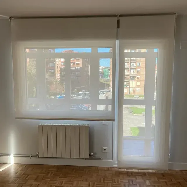 Un salón con radiador y un gran ventanal con persianas.