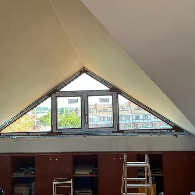 Una habitación con una ventana en forma de triángulo y una escalera.