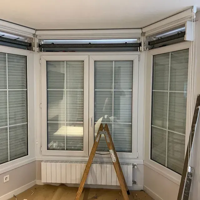 Una habitación con una escalera delante de una ventana.