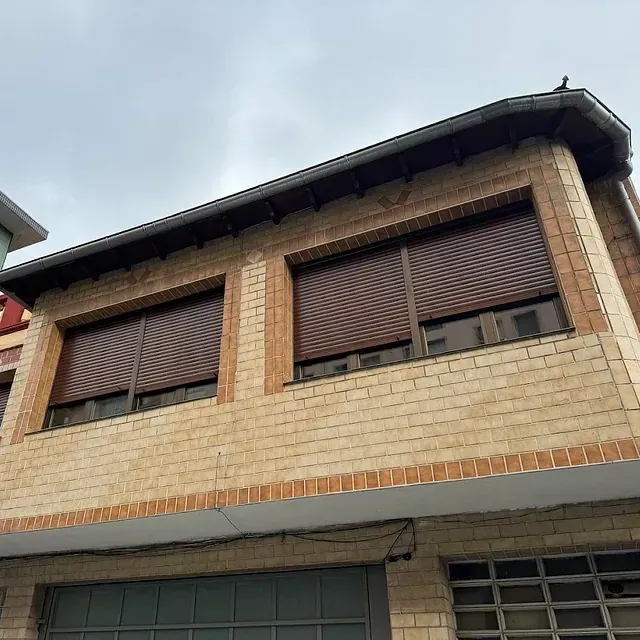Un edificio de ladrillo con persianas en las ventanas y techo.