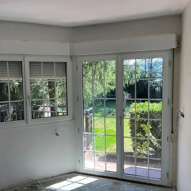 Una habitación con muchas ventanas y una puerta corrediza de vidrio.