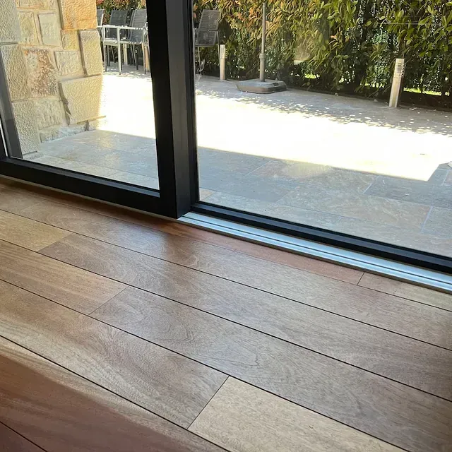 Un piso de madera junto a una puerta corrediza de vidrio.