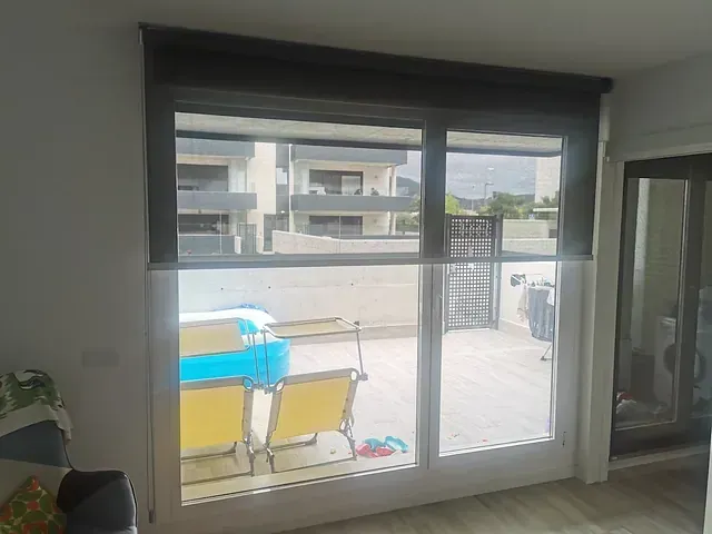 Una sala de estar con una puerta corrediza de vidrio que conduce a un balcón.