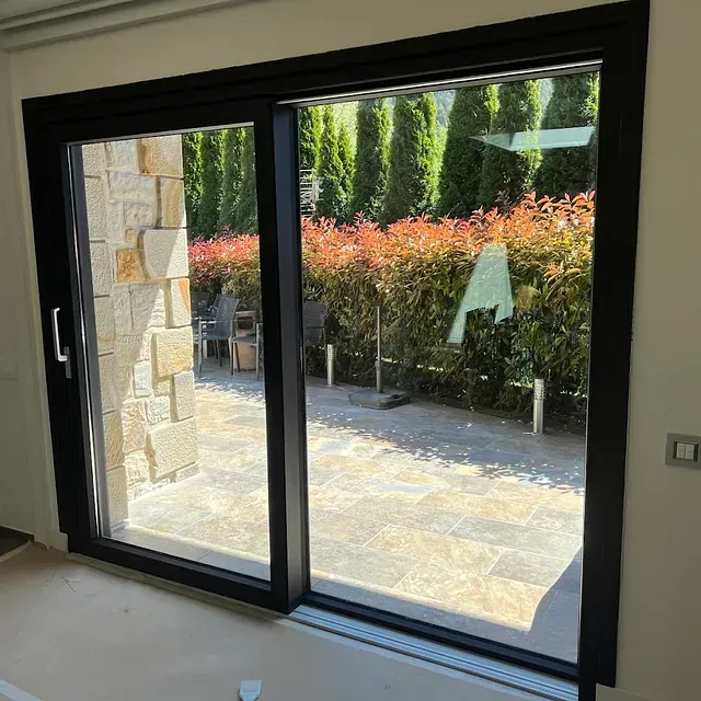 Una puerta corrediza de vidrio se abre a un patio con árboles al fondo.