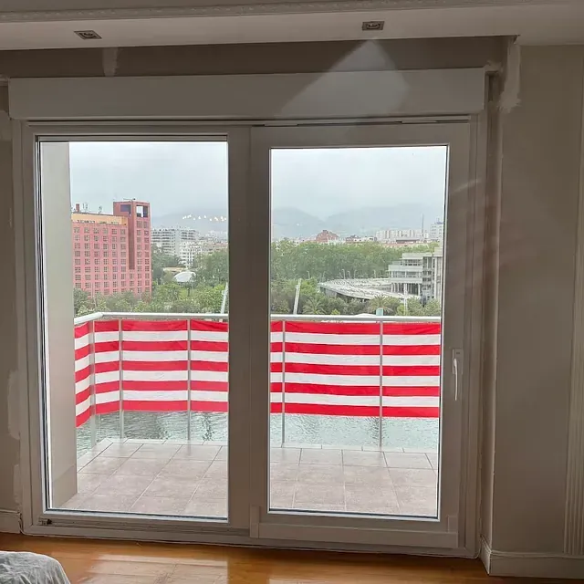 Un dormitorio con un balcón con barandilla de rayas rojas y blancas.