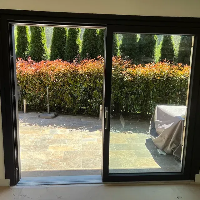 Una puerta corrediza de vidrio se abre a un patio con árboles al fondo.