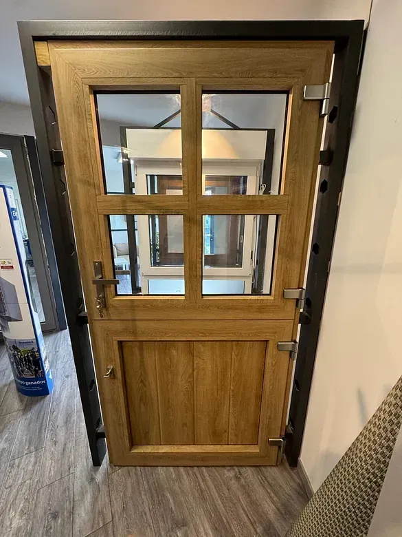 Una puerta de madera con cuatro ventanas está colocada sobre un piso de madera en una habitación.