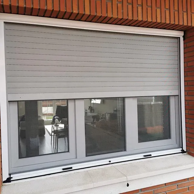 Una ventana con una persiana está en un edificio de ladrillo.