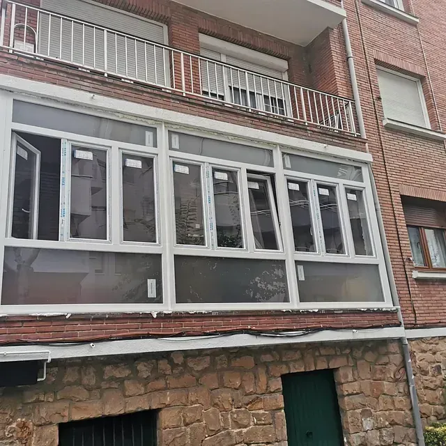 Un edificio de ladrillo con balcón y muchas ventanas.