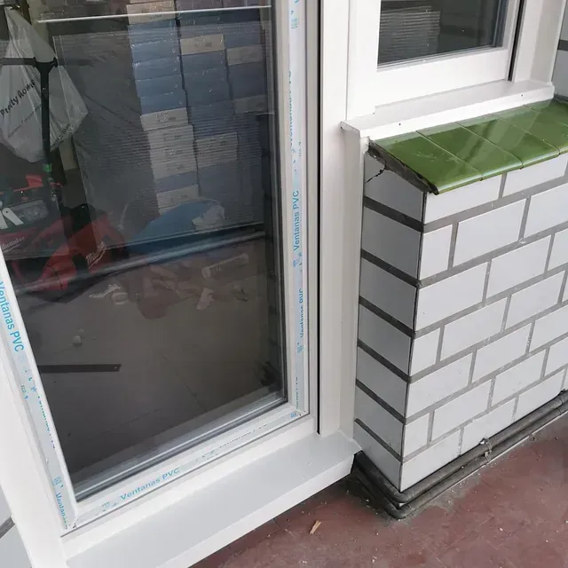 Una pared de ladrillo blanco junto a una ventana blanca