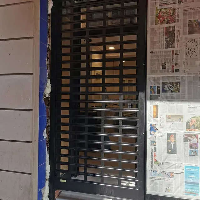 Una ventana con persiana está rodeada de periódicos.