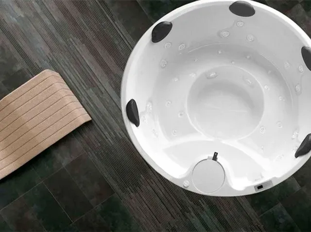 Un cuenco blanco reposa sobre un suelo de madera al lado de una silla de madera.