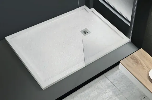 Un plato de ducha blanco en un baño junto a un espejo.