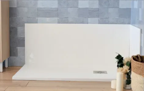 Una cabina de ducha blanca en un baño al lado de una cesta de flores y velas.