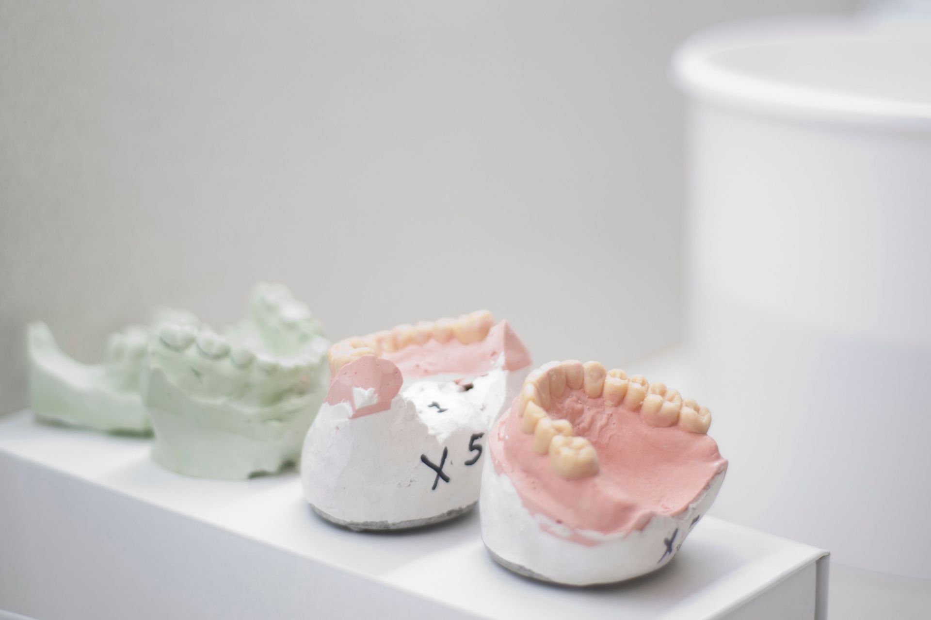 Tres modelos dentales están sentados sobre una mesa blanca.