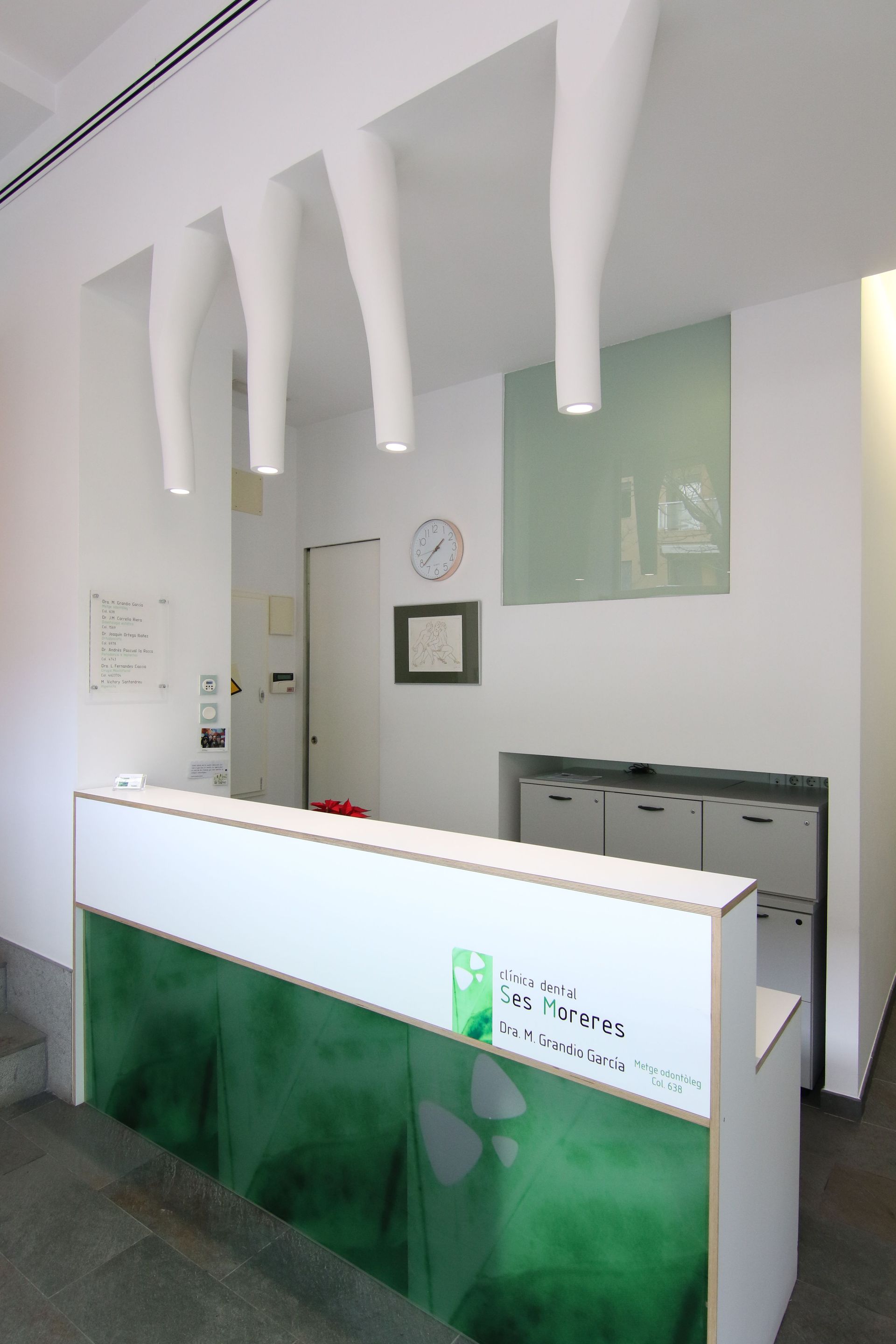 Un mostrador de recepción verde y blanco con un reloj en la pared.