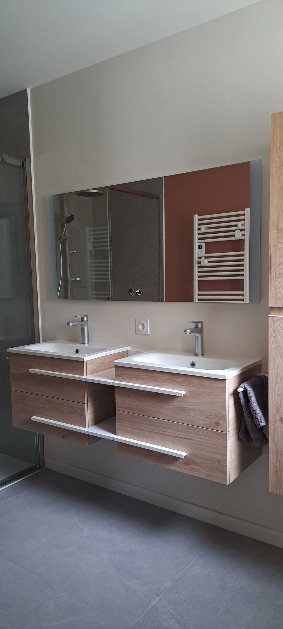 Salle de bains avec meuble-lavabo double en bois, grand miroir et porte-serviettes.