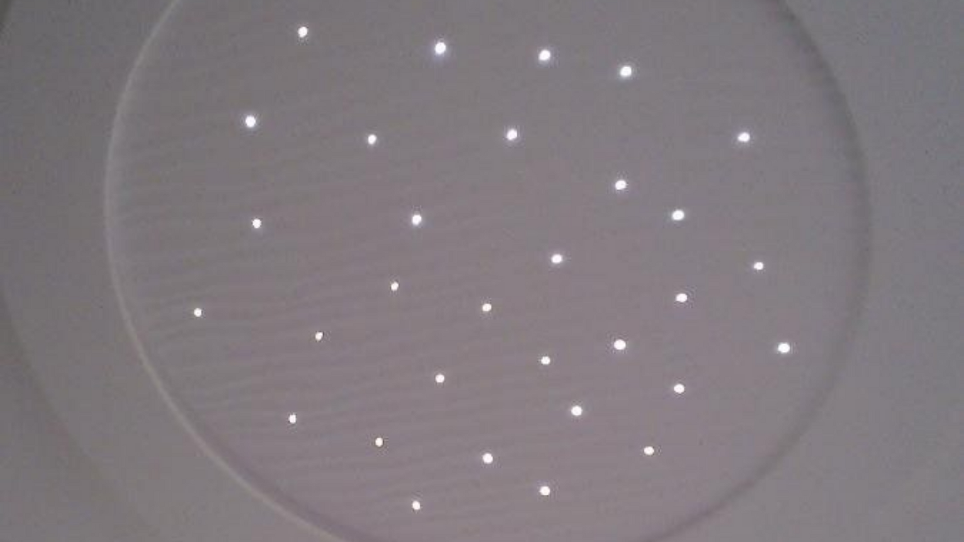 Plafond blanc orné de petites lumières vives évoquant un ciel étoilé.