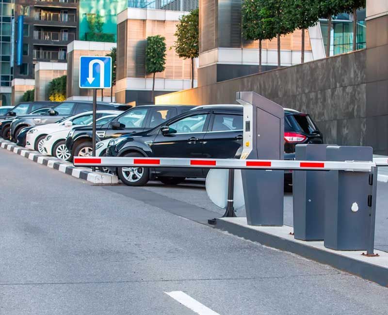 Aparcamiento con coches, puerta de entrada y señal de retorno. Coches blancos y negros aparcados detrás de la puerta.