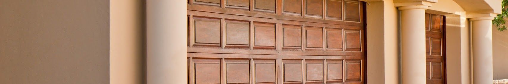 Puerta de madera ornamentada, enmarcada por pilares blancos, en la entrada de un edificio.