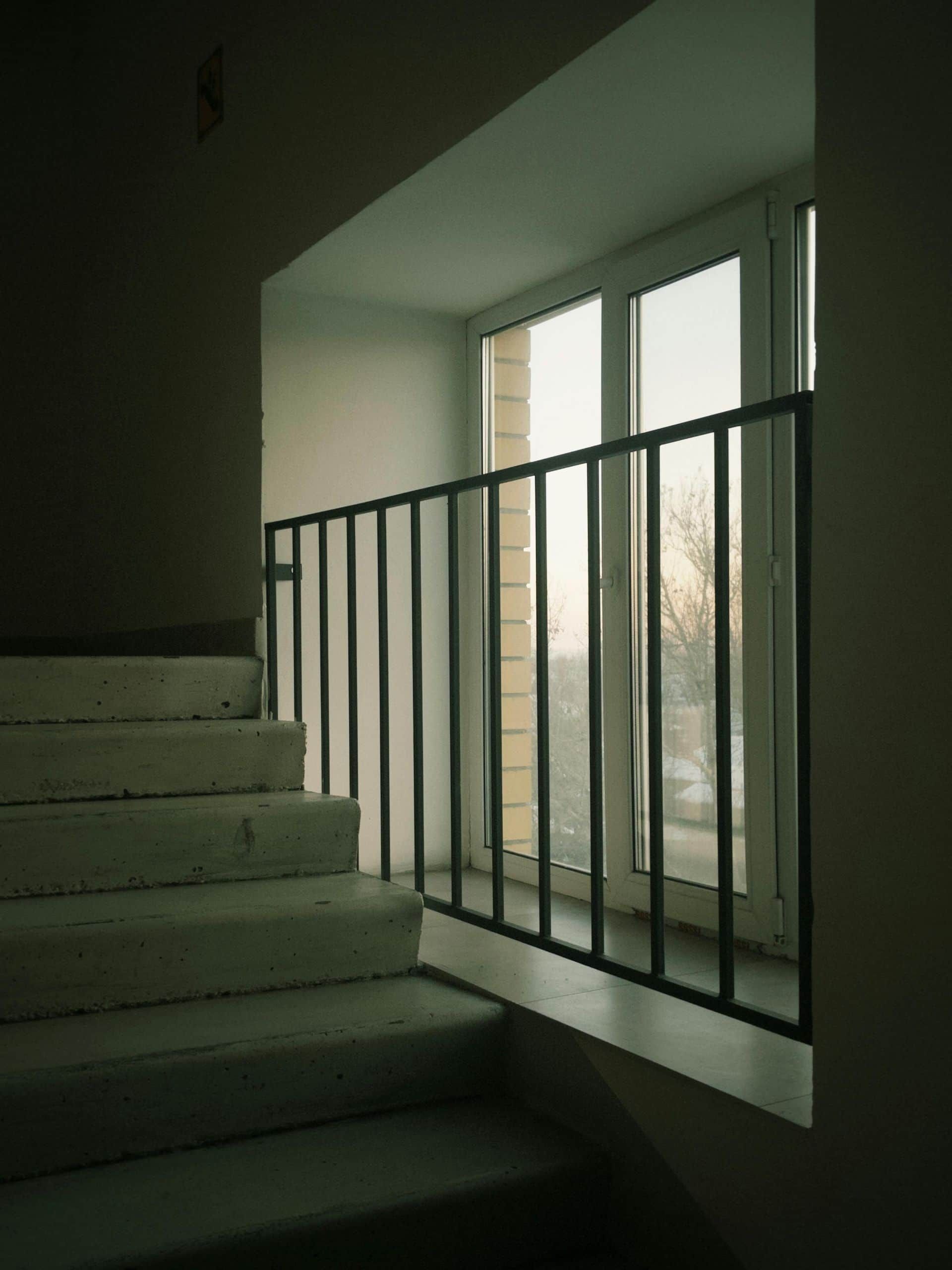 Escalera en un edificio con barandilla de metal negra junto a una ventana.