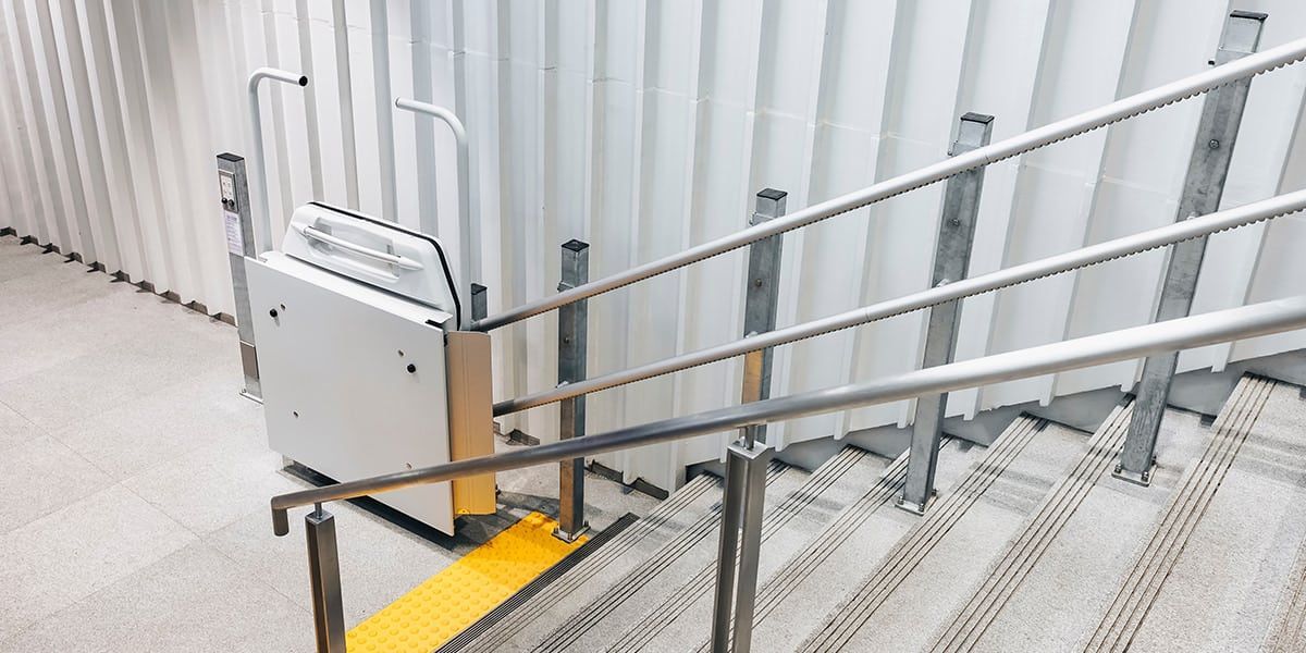 Escalera de hormigón blanco con pasamanos rojos.