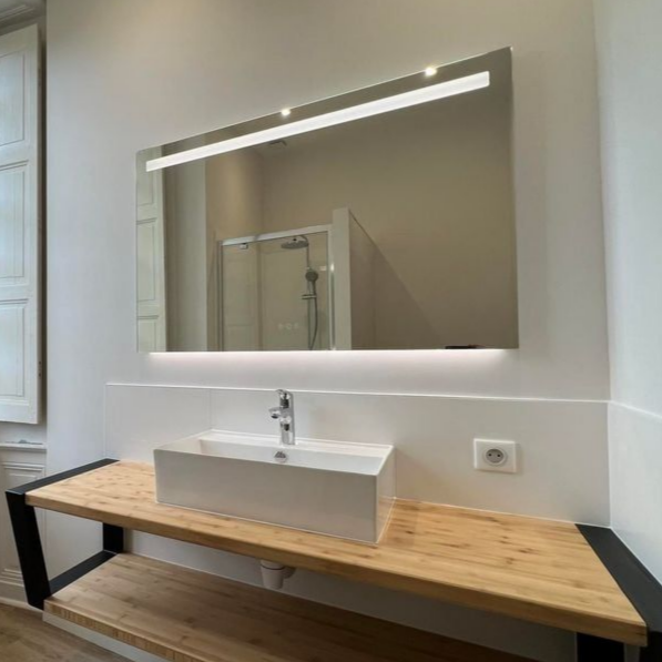 Salle de bains moderne avec miroir rectangulaire et meuble-lavabo suspendu en bois avec lavabo rectangulaire blanc.