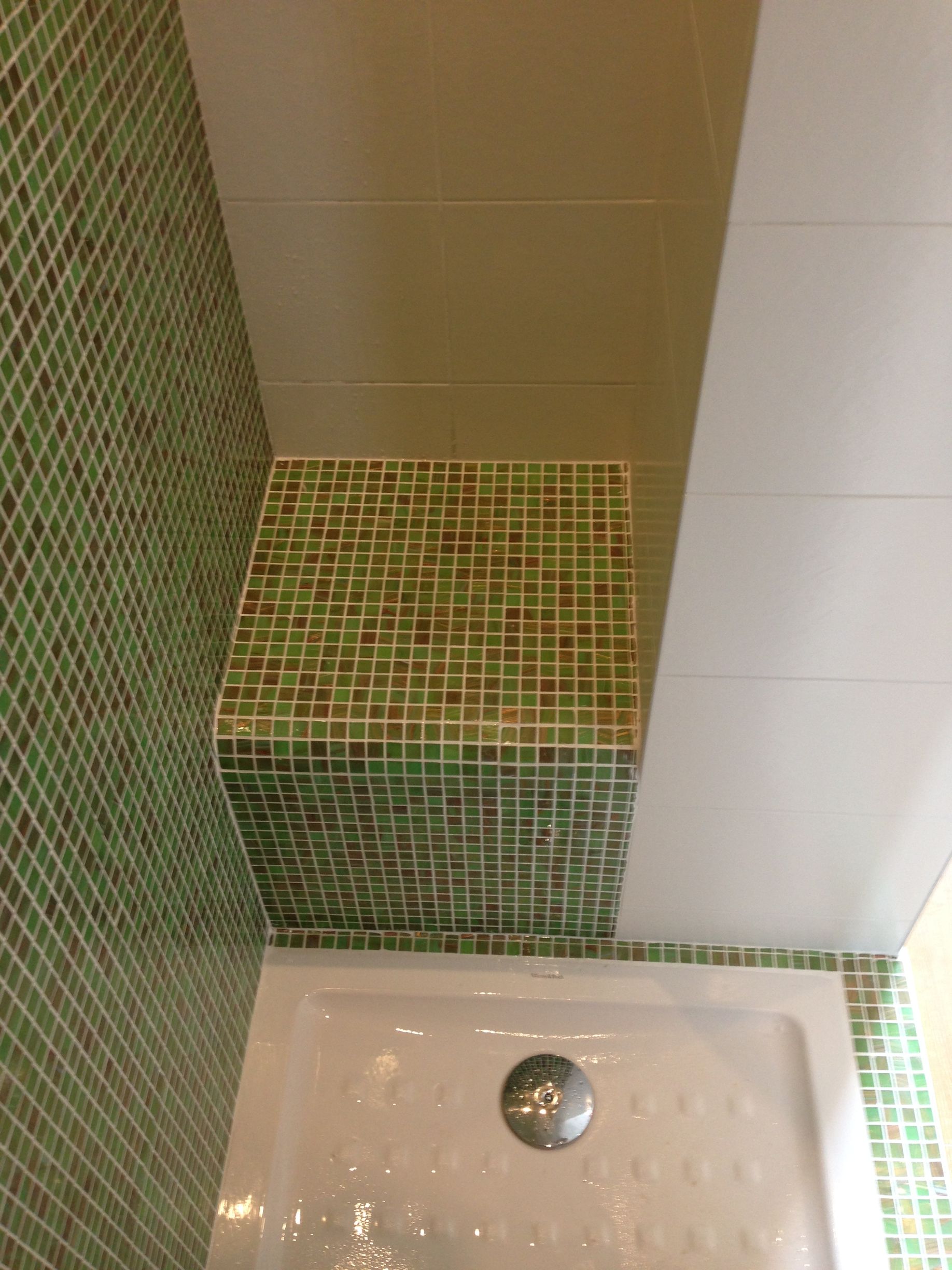 Parois de douche en mosaïque verte, plafond et receveur de douche blancs.
