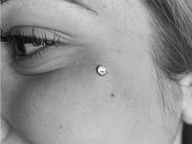 Una fotografía en blanco y negro del rostro de una mujer con un piercing.