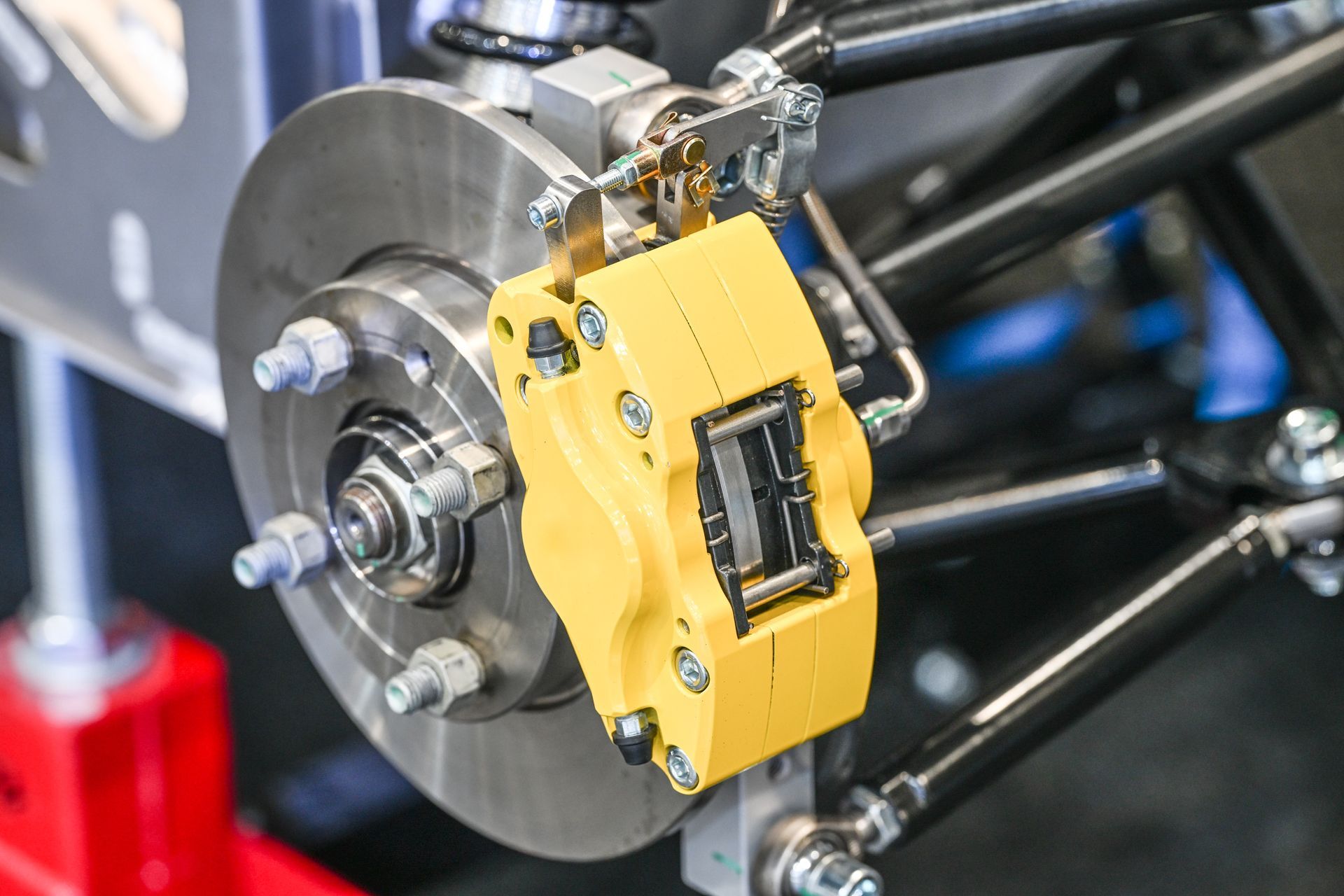 Gros plan sur un étrier de frein haute performance jaune vif monté sur un disque en acier ventilé d'une voiture de course.