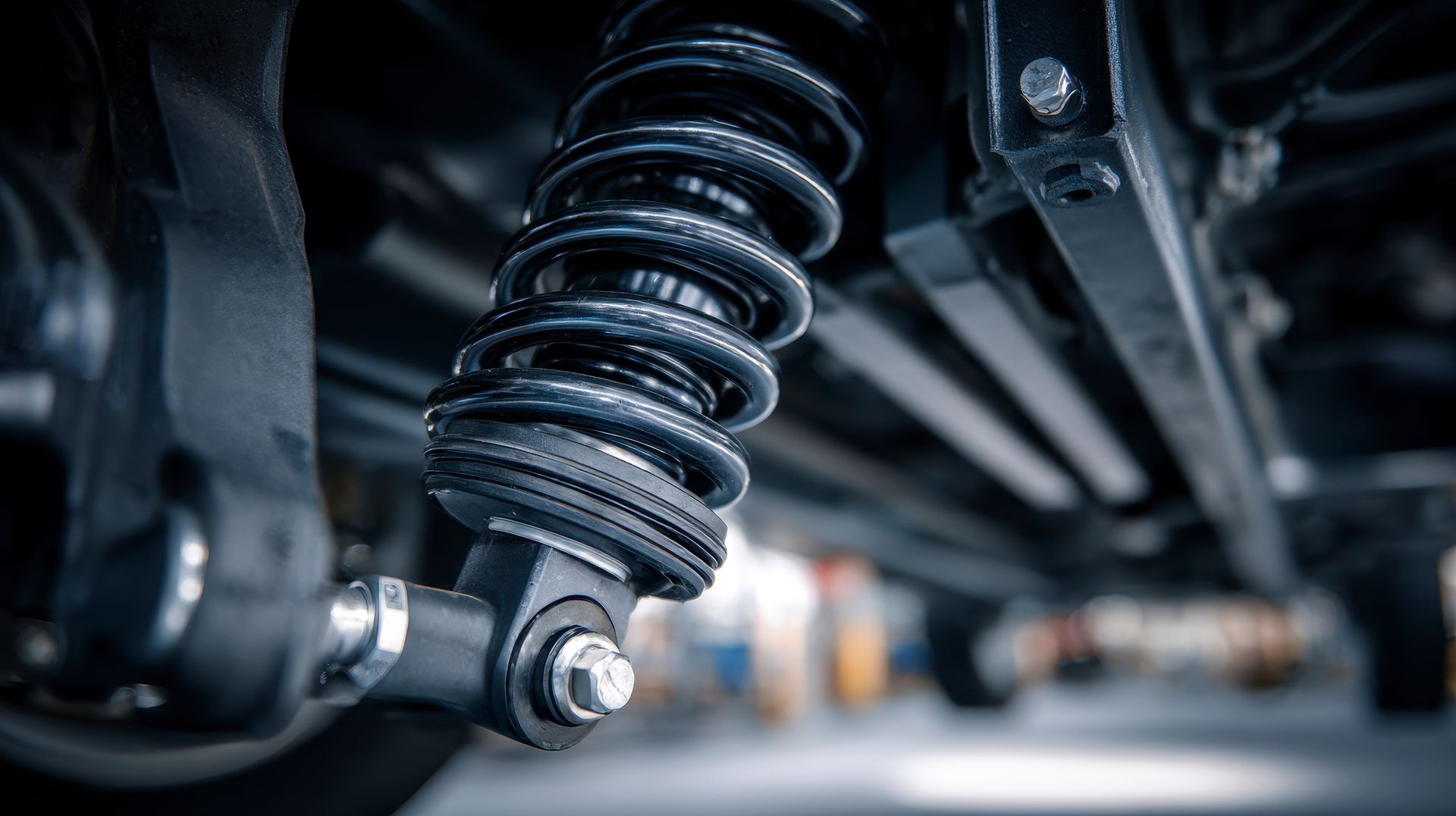 Gros plan, vue en contre-plongée d'un système de suspension à ressorts hélicoïdaux et de composants de châssis automobiles sombres.